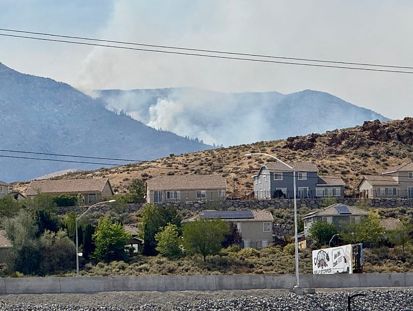 Smoke billows in the distance as a wildfire burns in Reno, 23 August, 2026