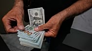 صراف يعدّ أوراقًا نقدية من فئة الدولار الأميركي في ساحة الفردوسي، أحد أبرز مراكز تداول العملات الأجنبية وسط العاصمة الإيرانية طهران، الاثنين 24 آب/أغسطس 2026. 