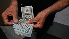 صراف يعدّ أوراقًا نقدية من فئة الدولار الأميركي في ساحة الفردوسي، أحد أبرز مراكز تداول العملات الأجنبية وسط العاصمة الإيرانية طهران، الاثنين 24 آب/أغسطس 2026. 