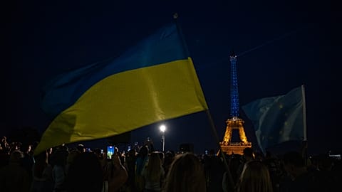 Persone sventolano bandiere ucraine ed europee con la Torre Eiffel illuminata con i colori ucraini a Parigi per il Giorno dell'indipendenza dell'Ucraina, lunedì 24 agosto 2026.