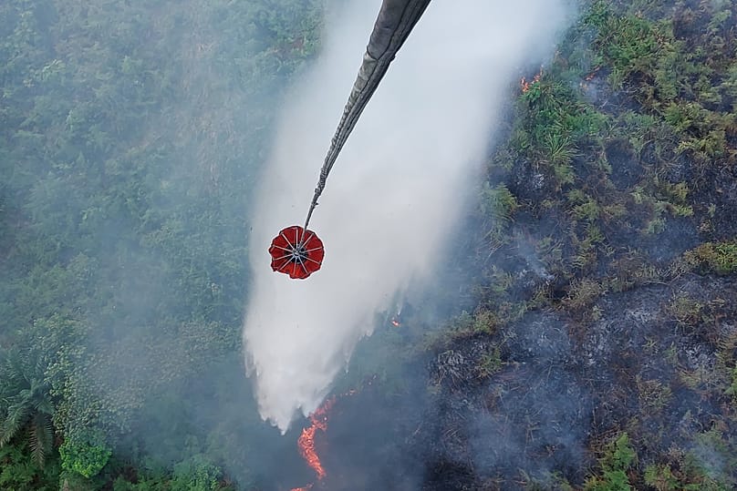 A helicopter conducts water bombing to extinguish a wildfire burning through a peatland field in Danau Lamo, 24 August, 2026