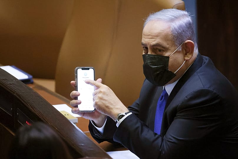 رئيس الوزراء الإسرائيلي بنيامين نتنياهو يحمل هاتفاً محمولاً خلال جلسة للكنيست، في 2 حزيران 2021.