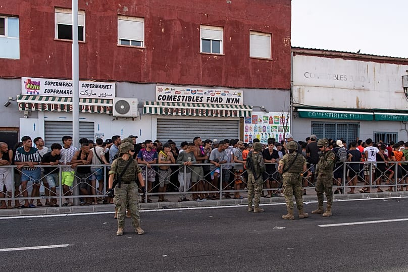 Des migrants attendent l'ouverture d'un magasin après avoir traversé la frontière depuis le Maroc pour rejoindre l'enclave espagnole de Ceuta, le 31 juillet 2026