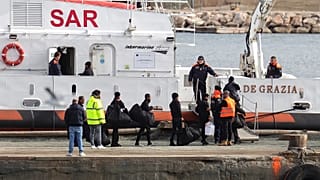 Migrants board an Italian Coast Guard vessel as part of a transfer operation from the asylum processing centres at the port of Shengjin, Albania.