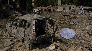 A local resident walks past destroyed vehicles and scattered debris the day after a Russian missile and drone attack in Kyiv. 