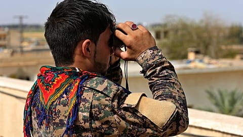 FILE: A Syrian Democratic Forces (SDF) fighter looks through his binoculars at an airstrike that hit an IS terrorist group position in Raqqa, 22 June 2017