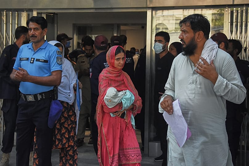 A woman carries her newborn baby out from a nursery in the gynaecology ward of a hospital following a fire in Islamabad, 26 August, 2026