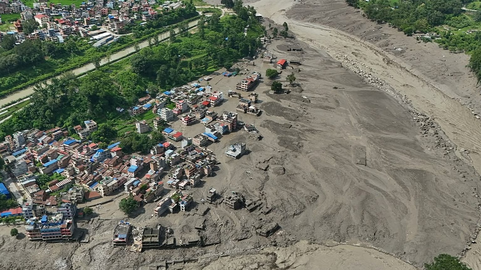 Damaged houses stand precariously near the banks of the Trishuli River after flash floods in the Nuwakot district, 26 August, 2026