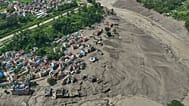 Damaged houses stand precariously near the banks of the Trishuli River after flash floods in the Nuwakot district, 26 August, 2026