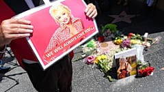 Actor Gregg Donovan holds a poster over Dolly Parton's star on the Hollywood Walk of Fame on Tuesday, Aug. 25, 2026, in Los Angeles.