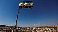 صورة أرشيفية-يرفرف العلم السوري فوق مبنى في ضواحي مدينة حلب، سوريا، يوم الثلاثاء 12 يونيو/حزيران 2012.
