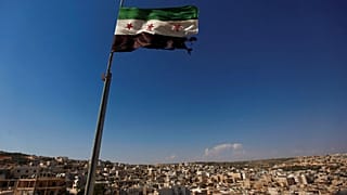 صورة أرشيفية-يرفرف العلم السوري فوق مبنى في ضواحي مدينة حلب، سوريا، يوم الثلاثاء 12 يونيو/حزيران 2012.