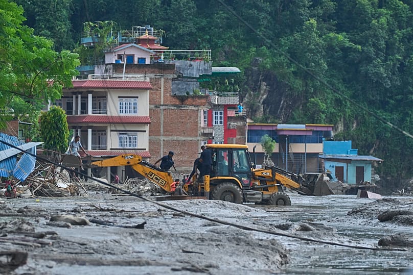 Rescuers use earthmovers to reach submerged houses after flash flooding along the Trishuli River in Nepal's Nuwakot district, Wednesday, Aug. 26, 2026. (AP Photo/Niranjan Shre