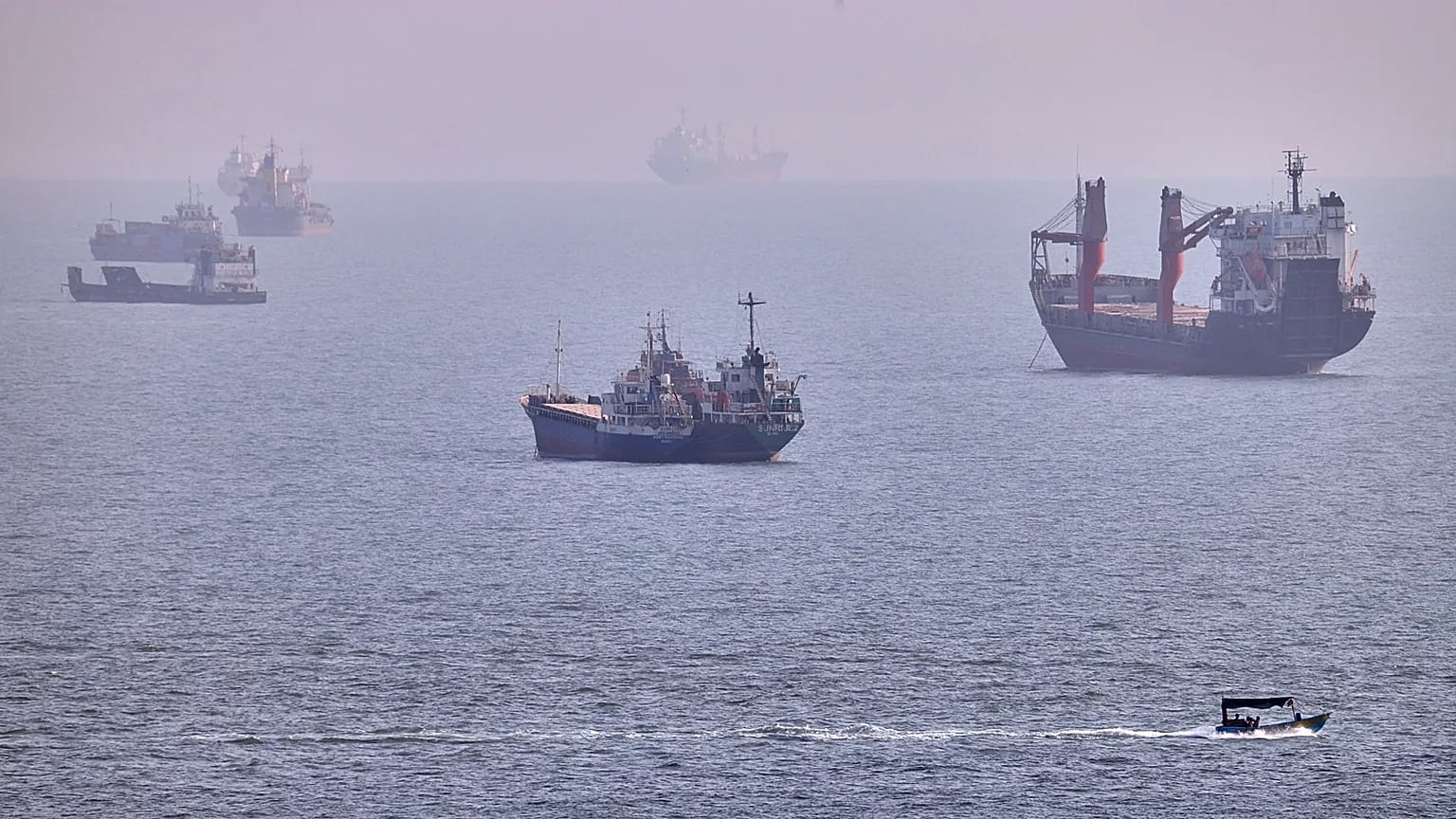 A small boat sails past cargo ships and other commercial vessels anchored in the Strait of Hormuz off Bandar Abbas, Iran, Wednesday, Aug. 5, 2026. (Amirhosein Khorgooi/ISNA vi
