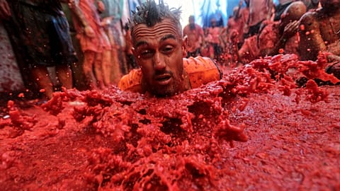 A man throws himself over a pool of tomatoes during the annual "Tomatina" tomato fight fiesta