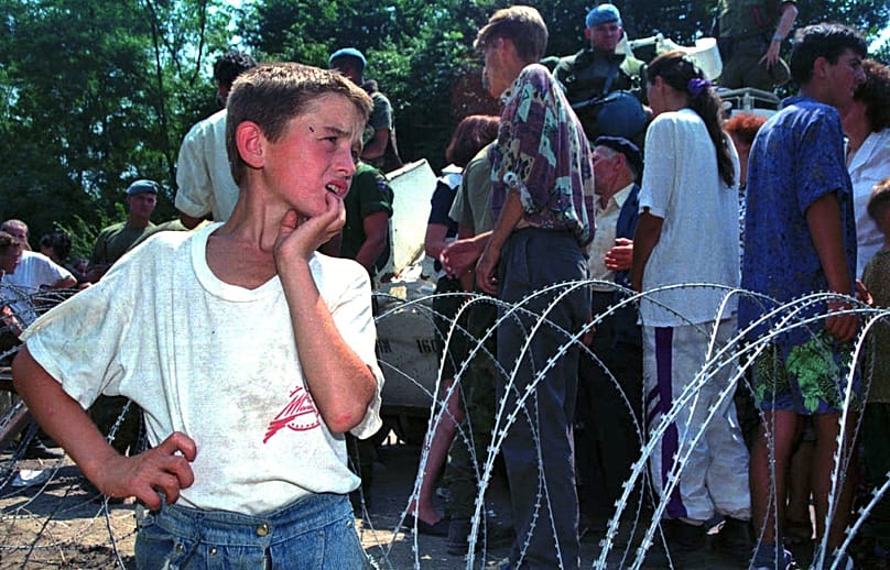 FILE: A young refugee from Srebrenica watching as others pass in a UN armoured vehicle as they arrive at a U.N. base 12 kms south of Tuzla, 13 July 1995