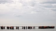 Migrants walk in the water to board a small boat and to reach Britain in Gravelines, 6 November, 2025 