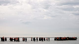 Migrants walk in the water to board a small boat and to reach Britain in Gravelines, 6 November, 2025 