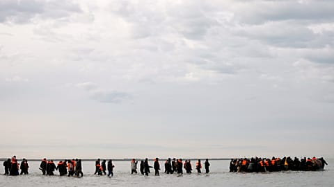 Migrants walk in the water to board a small boat and to reach Britain in Gravelines, 6 November, 2025 