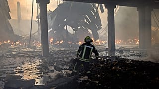 A firefighter tries to extinguish a fire in a destroyed warehouse after Russian drone attacks on the outskirts of Kyiv, 27 August, 2026