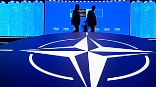 Two men walk past the NATO logo during the NATO Defence Industry Forum at the NATO summit in Ankara, 7 July, 2026