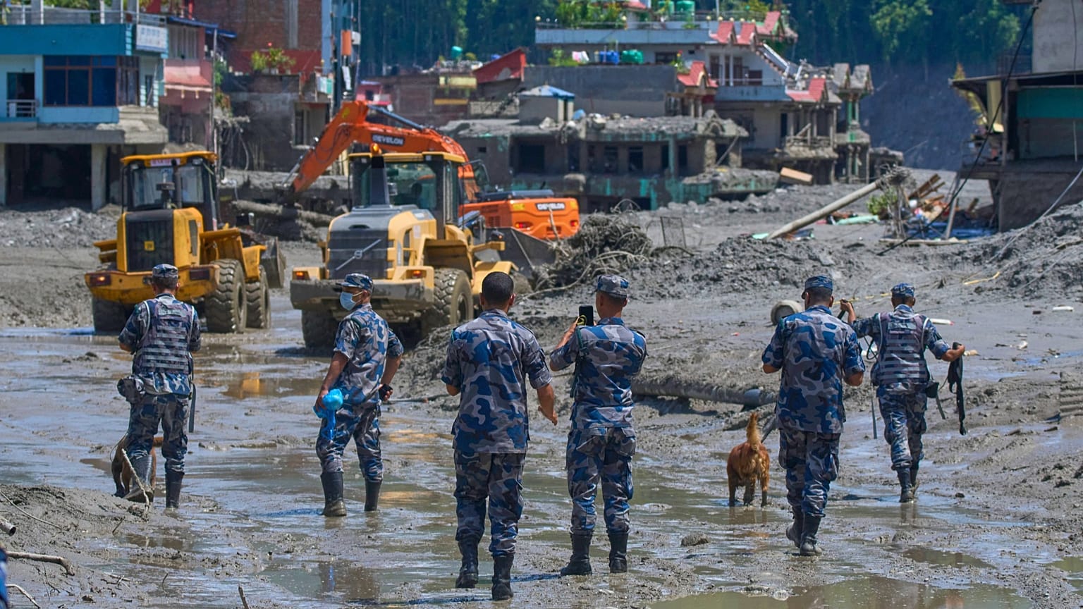Nepalese policemen watch as earthmovers clear the debris of flash flooding in Nepal's Nuwakot district, 27 August, 2026