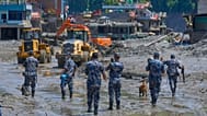 Nepalese policemen watch as earthmovers clear the debris of flash flooding in Nepal's Nuwakot district, 27 August, 2026
