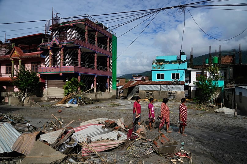 People walk past damage in the aftermath of flash floods in Devighat in the Nuwakot district in Nepal, 27 August, 2026