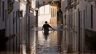 A resident walks along a flooded street in Lora del Rio, southern Spain, Thursday, Dec. 9, 2010.
