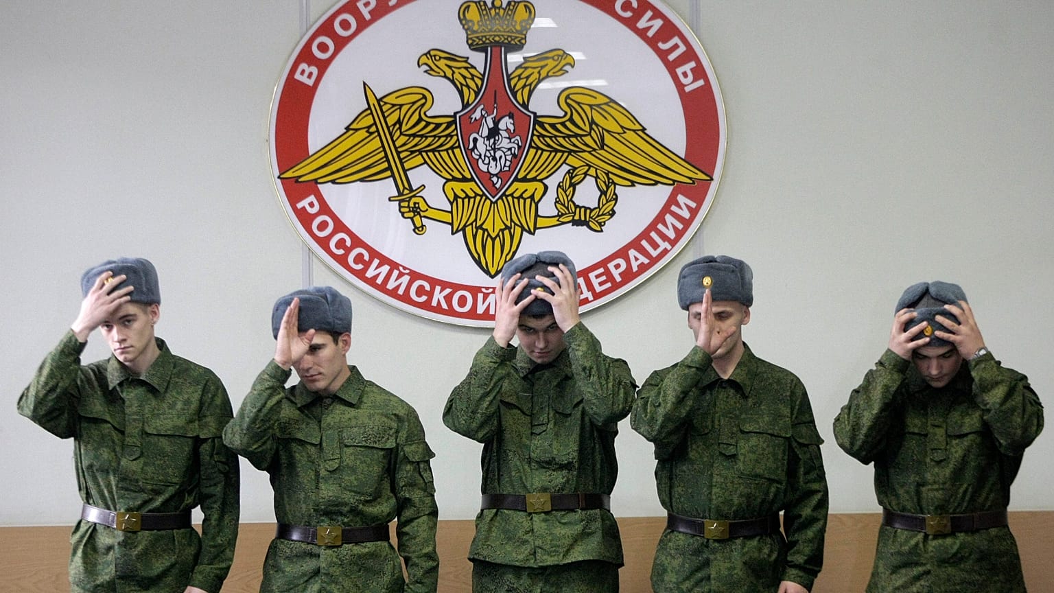 ARQUIVO: Recrutas russos ajustam os bonés sob letreiro “Forças Armadas da Federação Russa” num posto de recrutamento em Moscovo, 26 maio 2010