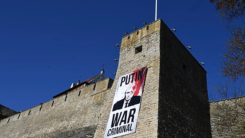 FILE: A poster with an image of Russian President Vladimir Putin is seen on the wall of the Narva Castle opposite Russian border, in Narva, Estonia, Tuesday, May 9, 2023.