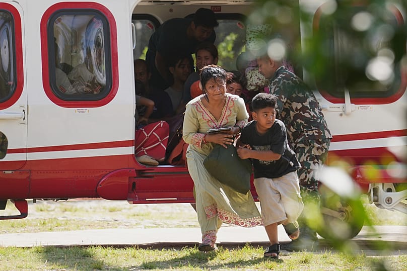 Soldaten der nepalesischen Armee helfen einer Familie beim Aussteigen aus einem Hubschrauber, Distrikt Nuwakot in Nepal, 28. August 2026 