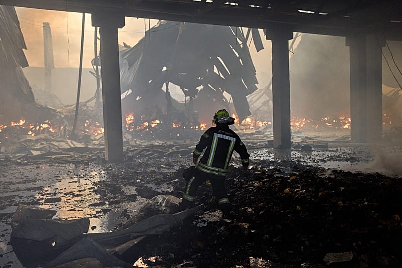 A firefighter tries to extinguish a fire in a destroyed warehouse after Russian drone attacks on the outskirts of Kyiv, Ukraine, Thursday, Aug. 27, 2026