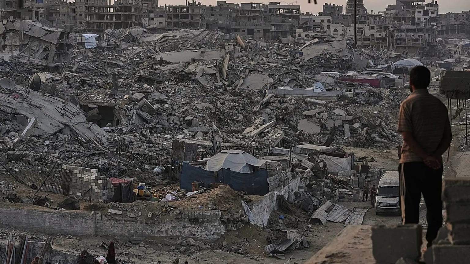فلسطينيون يسيرون وسط الدمار الذي خلفه الهجوم الجوي والبري الإسرائيلي في حي الشيخ رضوان بمدينة غزة