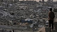 فلسطينيون يسيرون وسط الدمار الذي خلفه الهجوم الجوي والبري الإسرائيلي في حي الشيخ رضوان بمدينة غزة