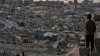 فلسطينيون يسيرون وسط الدمار الذي خلفه الهجوم الجوي والبري الإسرائيلي في حي الشيخ رضوان بمدينة غزة