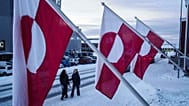 Women walk on a street in front of national flags in Nuuk, 14 January, 2026