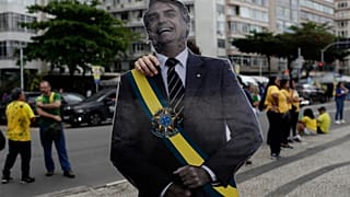 Um apoiante do candidato presidencial da oposição, Flávio Bolsonaro, exibe uma imagem do pai de Flávio Bolsonaro, o ex-presidente Jair Bolsonaro