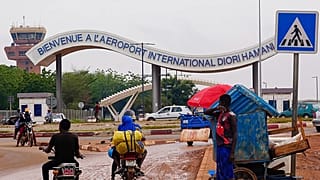 Des motocyclistes passent devant l'entrée de l'aéroport de Niamey, au Niger, le 8 août 2023.