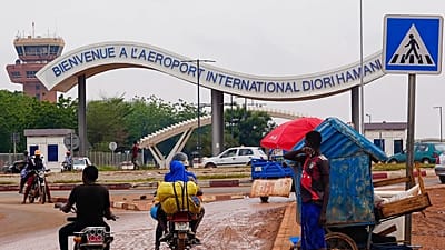 Des motocyclistes passent devant l'entrée de l'aéroport de Niamey, au Niger, le 8 août 2023.