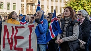 People hold a banner reading "No" as they listen to speakers at an "Afram Island," "Forward, Iceland," rally opposing the resumption of European Union accession talks