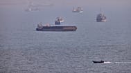 A small boat sails past cargo ships and other commercial vessels anchored in the Strait of Hormuz off Bandar Abbas, Iran, Wednesday, Aug. 5, 2026