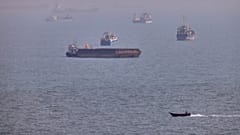 A small boat sails past cargo ships and other commercial vessels anchored in the Strait of Hormuz off Bandar Abbas, Iran, Wednesday, Aug. 5, 2026