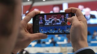 صحفي يصور شاشة تبث خطاباً مباشراً للرئيس الروسي بوتين بقمة منظمة شنغهاي في تيانجين الصينية، 1 سبتمبر 2025