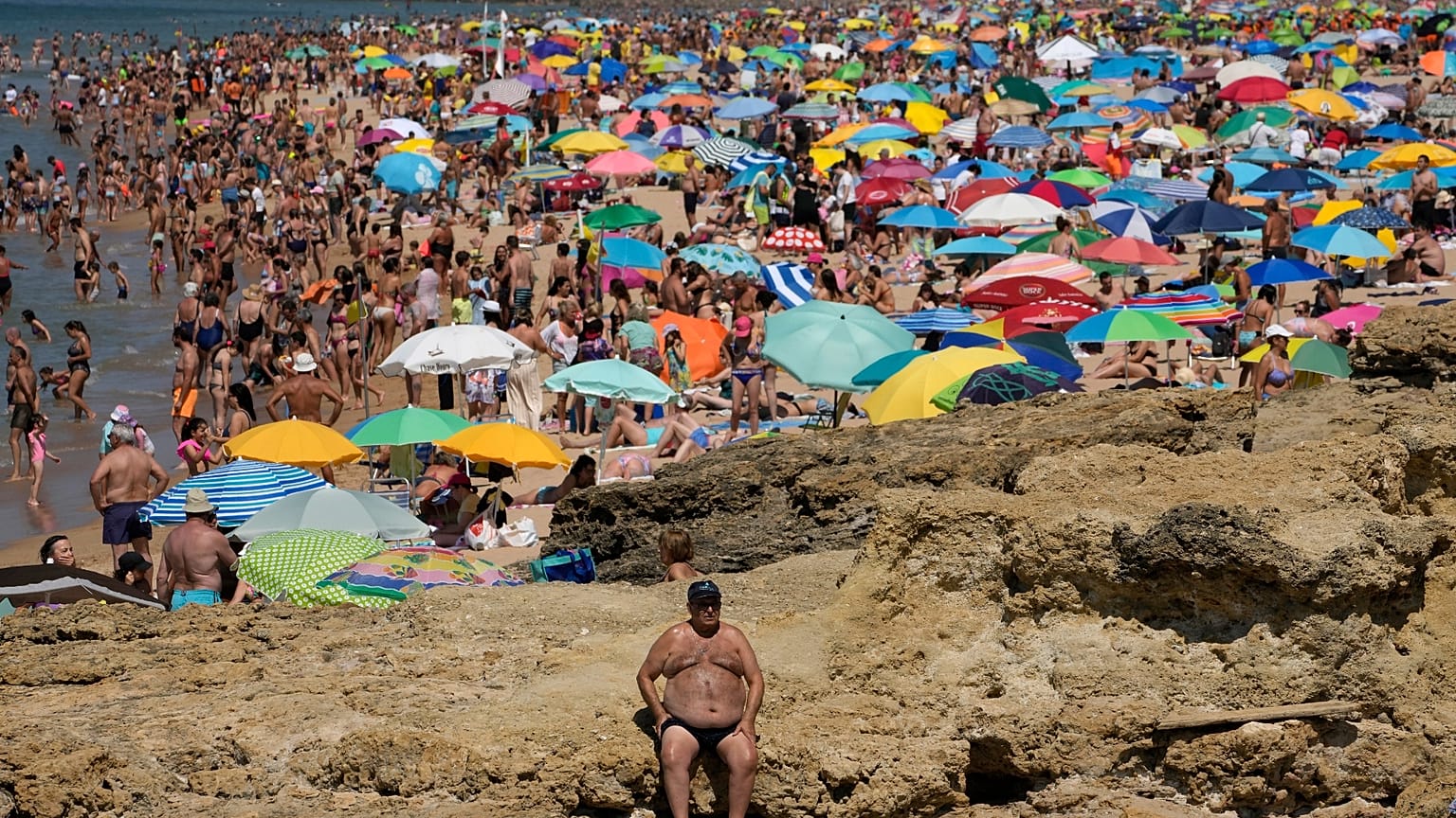 Um homem está sentado ao sol na praia de Carcavelos, nos arredores de Lisboa, na sexta-feira, 8 de julho de 2022
