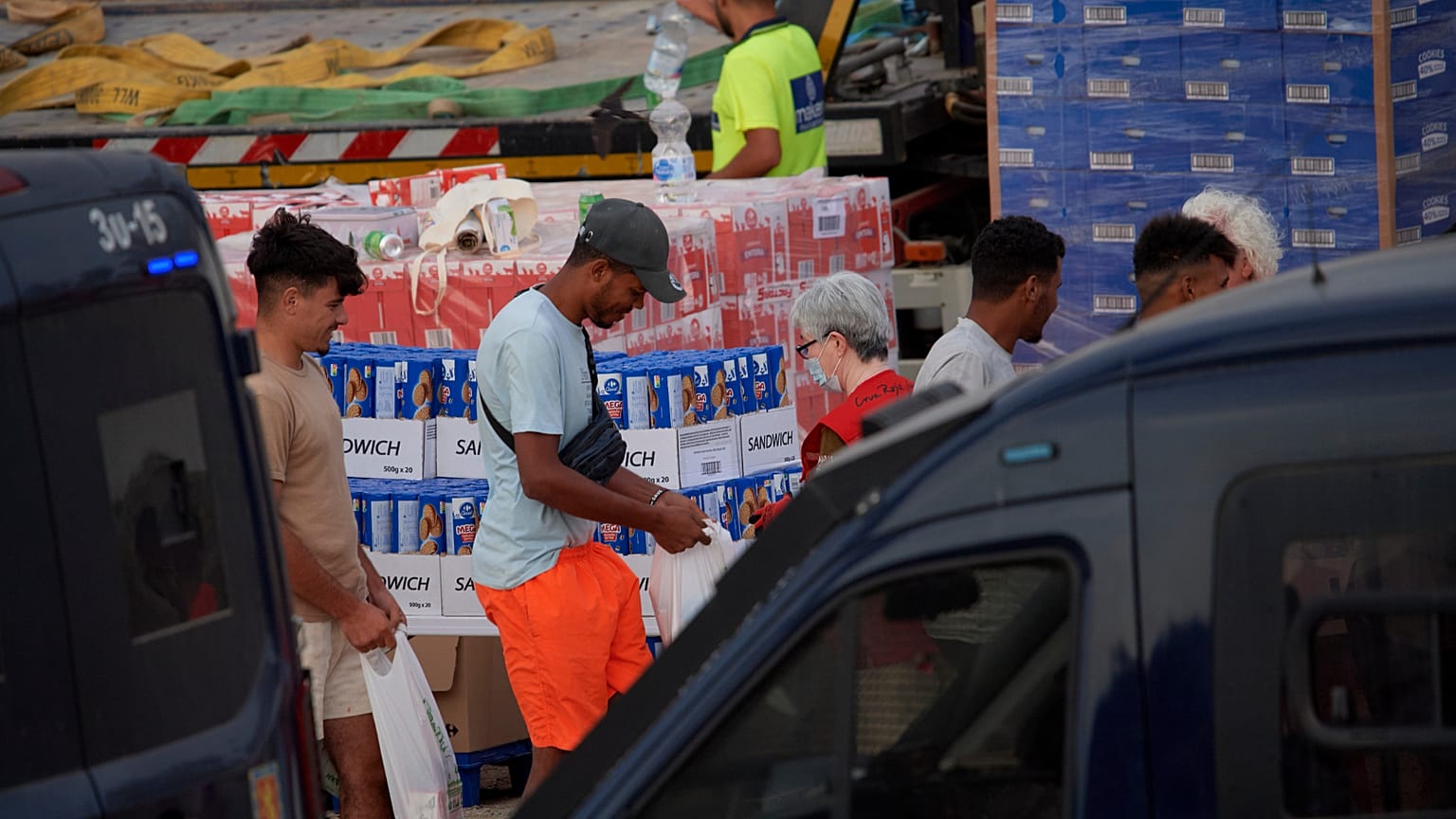 Unos migrantes reciben unos víveres de ayuda