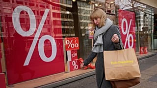 FILE. A woman walks with purchases past a store in Berlin, Germany, Jan. 2023