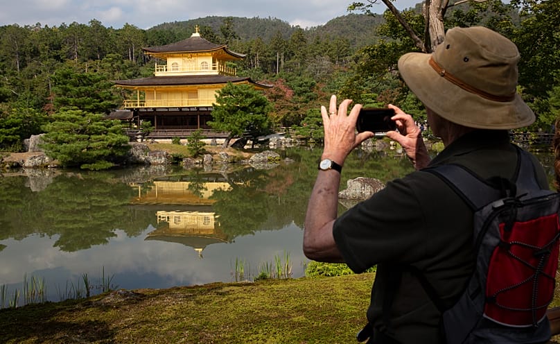 A tourist takes a picture of the famous Kinkakuji Temple or often called Golden Pavilion in Kyoto