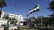 جنود سوريون يرفعون العلم الوطني السوري أمام مبنى وزارة الدفاع السورية، الذي تضرر بشدة جراء غارات جوية إسرائيلية يوم الأربعاء الماضي، في دمشق، سوريا، السبت 19 يوليو/تموز 2025. 