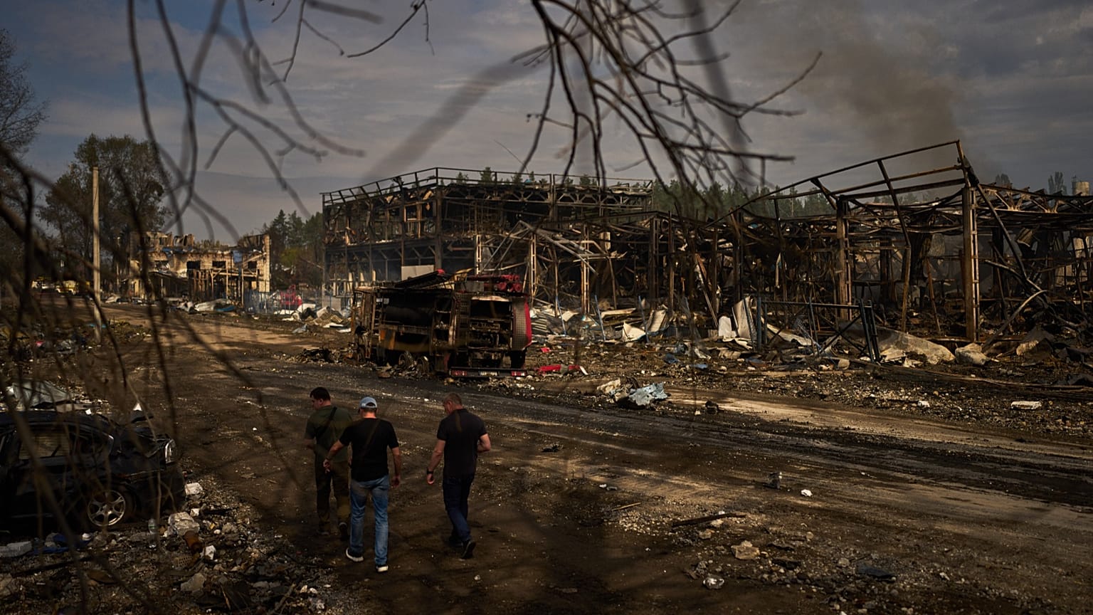 People walk past destroyed vehicles and debris scattered the day after a Russian attack struck a warehouse in Myla, 30 August, 2026